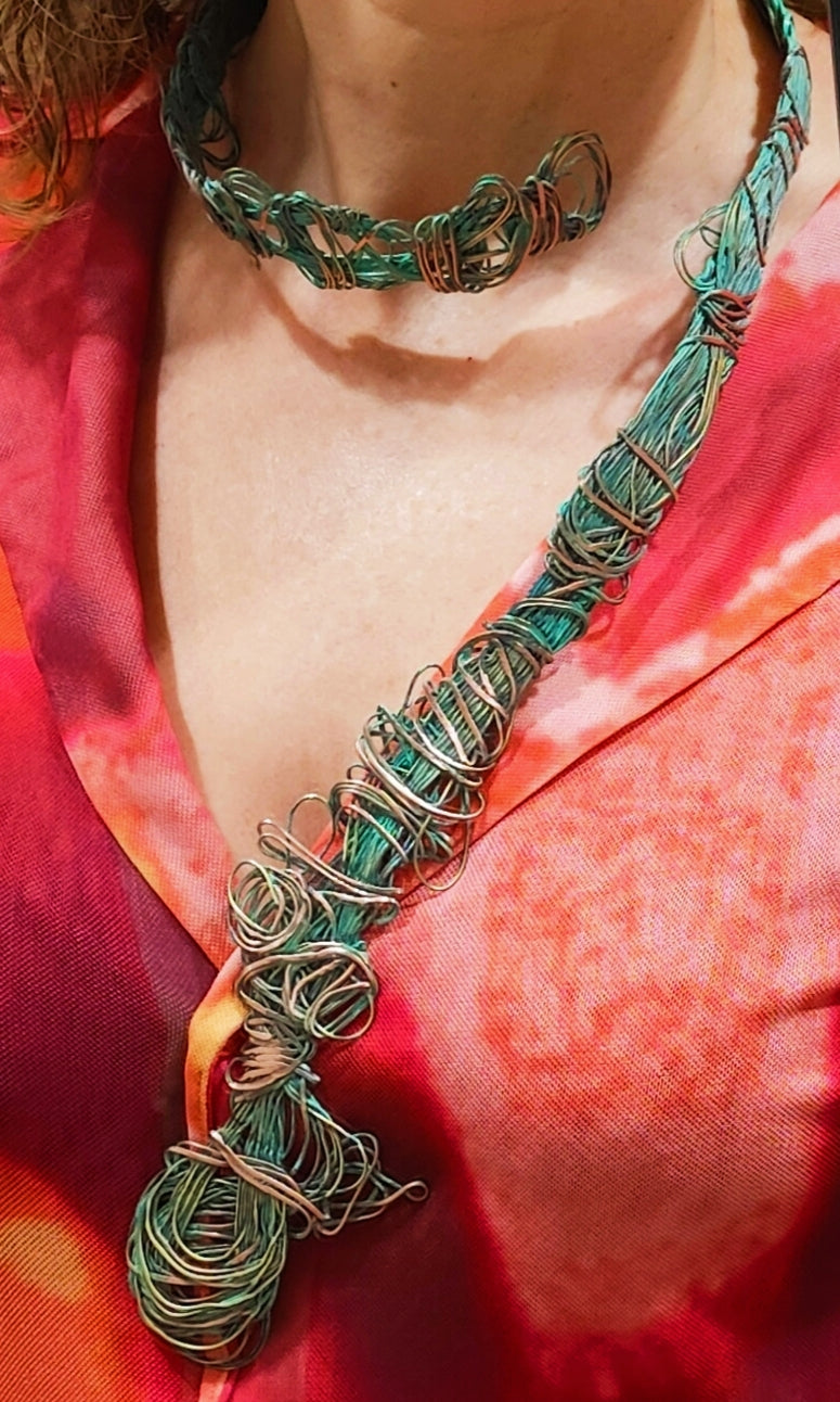 Collar de la colección Redes hecho de cobre y bronce. Inspirado en el Mediterráneo, el collar presenta un intrincado tejido metálico con tonos verdosos que evocan redes de pesca y texturas del fondo marino. La pieza combina rusticidad y elegancia, reflejando la creatividad y habilidad técnica en su diseño.
