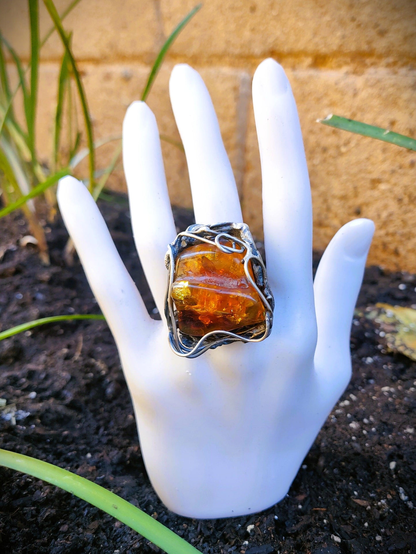 Primer plano del anillo ambar de plata en una mano de maniquín. Una pieza única y artesanal