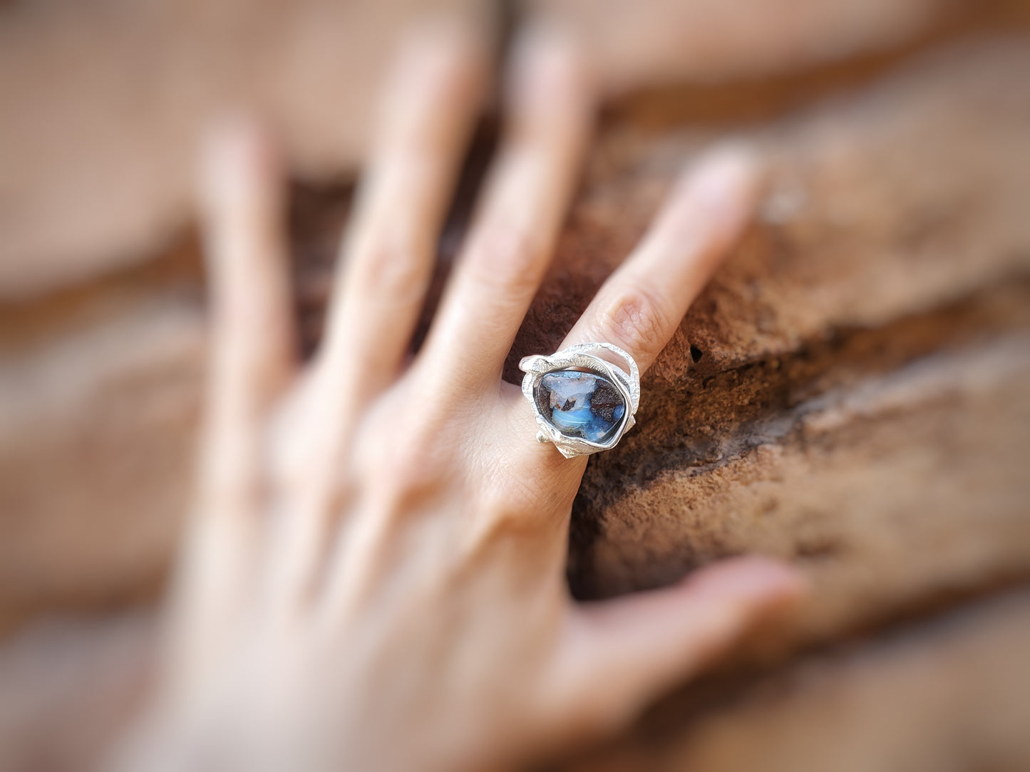 Primer plano del anillo de plata con la piedra ópalo Boulder en en un dedo.