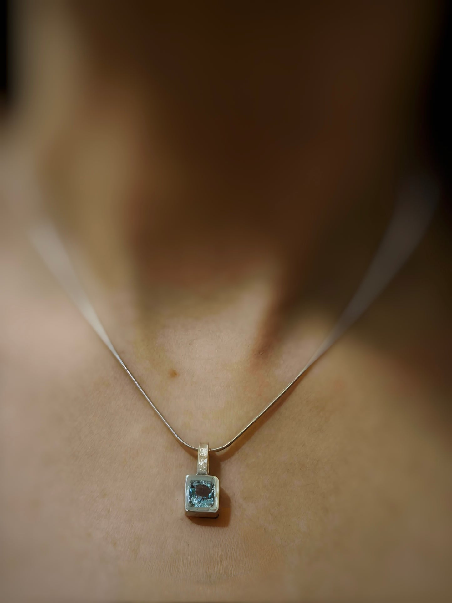"Colgante cuadrado de plata mate con topacio azul, joyería de autor y joyas artesanales."