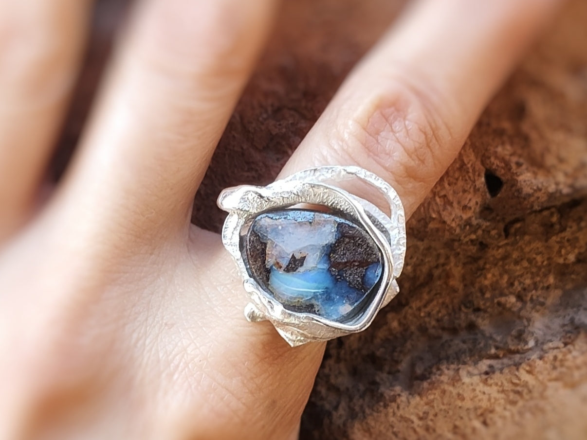 Primer plano del anillo de plata con la piedra ópalo Boulder en un dedo.