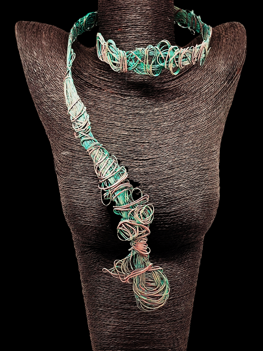 Primer plano del collar de la colección Redes, destacando el fino trabajo en cobre y bronce. Las tonalidades verdosas y el tejido intricante reflejan la inspiración marina, evocando redes de pesca y formas del fondo del mar, con un diseño rústico y elegante.
